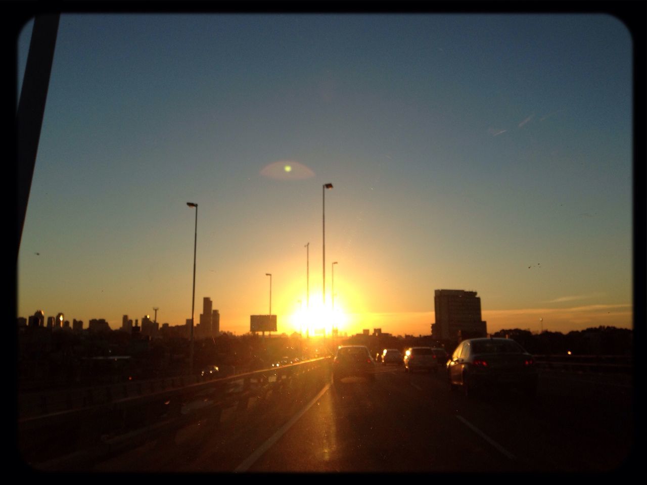 transportation, sunset, car, land vehicle, mode of transport, transfer print, road, sun, sky, auto post production filter, street, road marking, orange color, the way forward, street light, city, built structure, architecture, traffic, sunlight