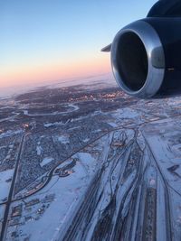 Cropped jet engine above landscape against sky during winter