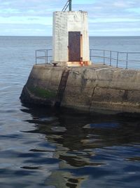 Lighthouse by sea against sky