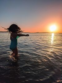 Full length of woman on beach against sky during sunset