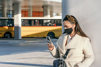 Young woman wearing black face mask in city. using mobile phone, covid, corona.