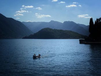 People on boat in river against sky