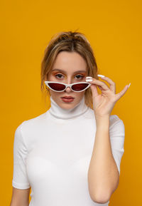 Portrait of a beautiful young woman against yellow background