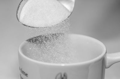 Close-up of sugar in spoon over cup