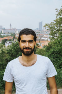 Portrait of smiling young man standing against plants