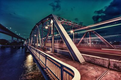 Blurred motion of vehicle on illuminated bridge over river at night