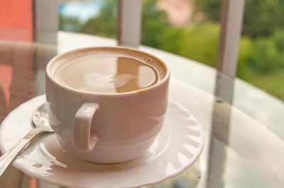 Coffee in a cup on a glass table, a balcony with a view of nature and the sea, 