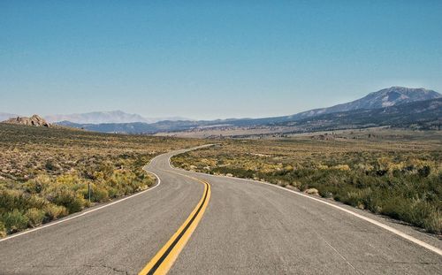 Empty road in desert against clear sky