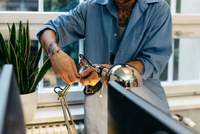 Midsection of man adjusting desk lamp at office