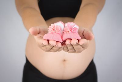 Close-up of hand holding ring over white background