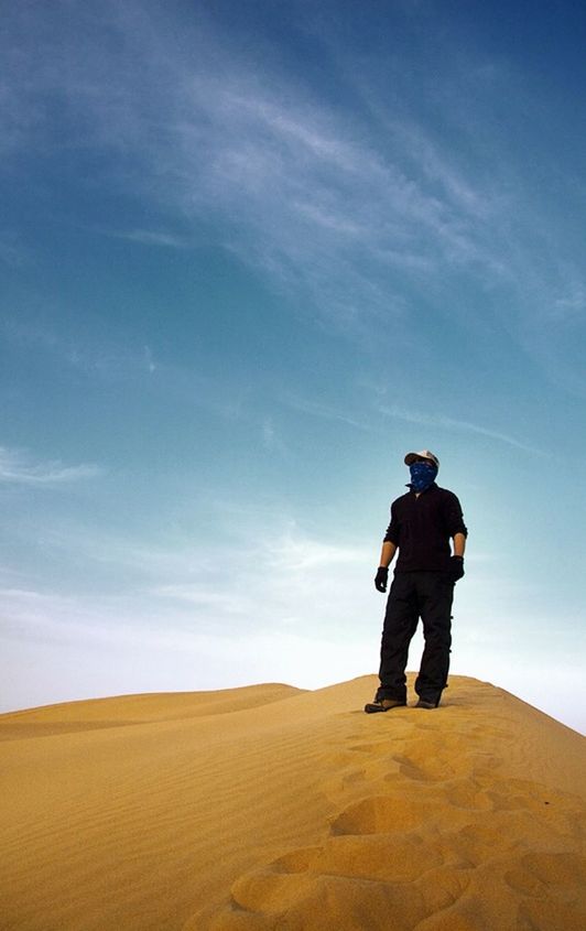 full length, sky, one person, leisure activity, real people, standing, beauty in nature, men, lifestyles, cloud - sky, nature, non-urban scene, land, casual clothing, day, scenics - nature, rear view, tranquility, sunlight, outdoors, arid climate