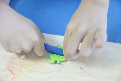 Cropped hand of person playing with clay on table at home