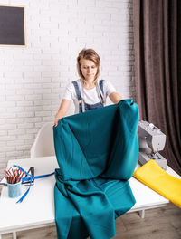 Portrait of young woman against wall at home