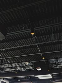 Low angle view of illuminated light bulb hanging on ceiling in building
