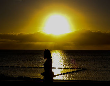 Silhouette man looking at sea against sky during sunset