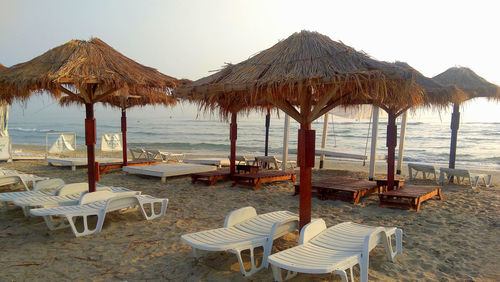 Chairs and table on beach against clear sky