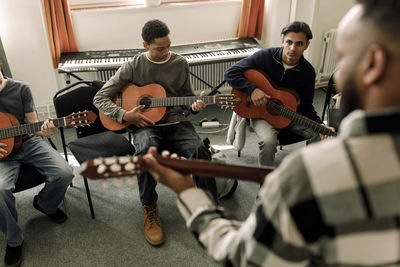 Male teenage students leaning guitar in music class at high school