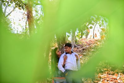 Young couple standing by trees in forest