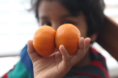 Close-up of boy holding orange fruits