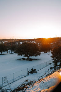 Scenic view of snow covered landscape against sky at sunset