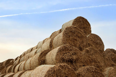 Low angle view of hay bales on rock against sky