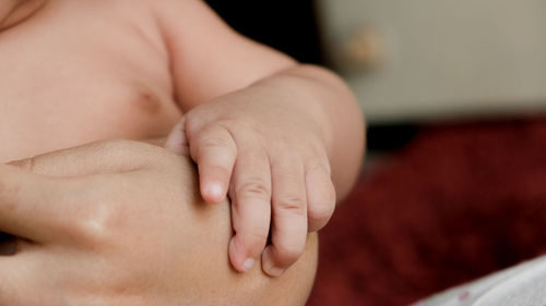 Parent hands holding newborn baby fingers, close up mother's hand holding their new born baby. 