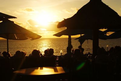 Silhouette people on beach against sky during sunset