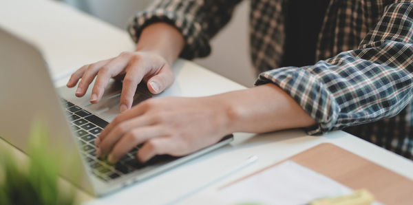 Midsection of man using laptop on table