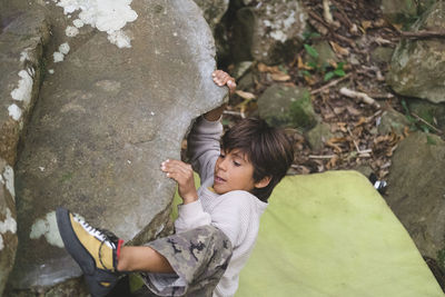 A little boy climbs a rock outdoors