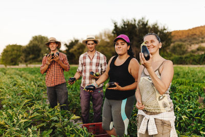 People holding vegetable while standing in farm