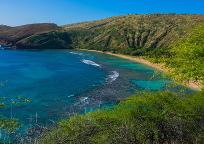 Scenic view of sea and mountains against clear blue sky