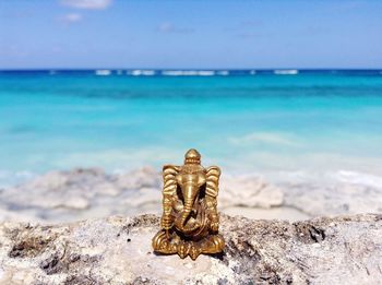 Close-up of ganesha statue on rock by sea against sky