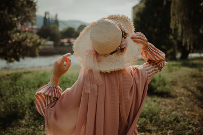 Midsection of woman wearing hat standing on field