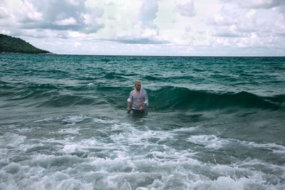 Man standing in sea against sky