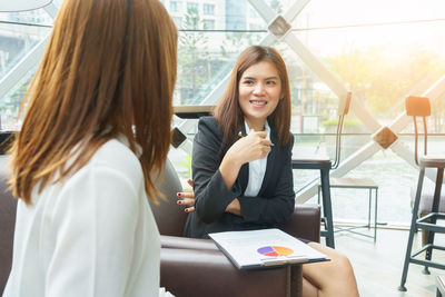 Businesswomen discussing over graph at cafe