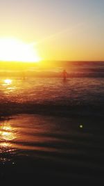 Silhouette person on sea against sky during sunset