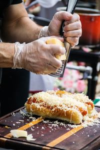 Midsection of man preparing hot dogs on kitchen counter