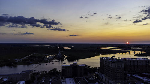 High angle view of buildings and sea against sky at sunset