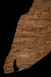 Silhouette man standing on rock at cave