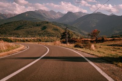 Road leading towards mountains against sky