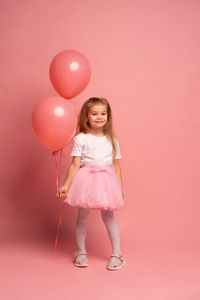 Portrait of young woman with balloons against yellow background