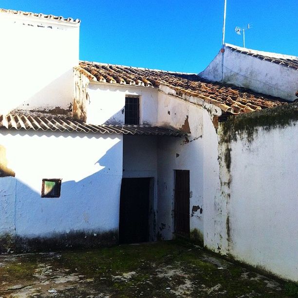 building exterior, architecture, built structure, house, blue, clear sky, residential structure, sunlight, day, outdoors, no people, residential building, copy space, wall, building, low angle view, sky, window, roof, grass