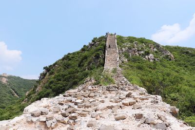 Low angle view of stone wall on mountain against sky