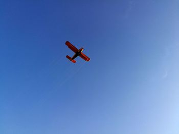 Low angle view of airplane against clear blue sky