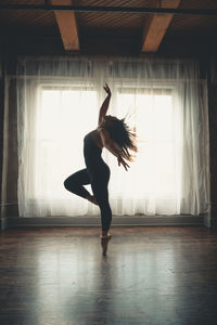 Full length of woman standing by window