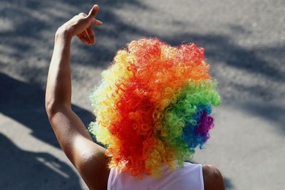 Rear view of man wearing colorful wig on street in city