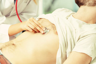 Midsection of female doctor examining patient chest at clinic