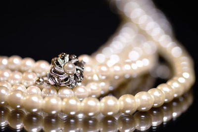 Close-up of pearl necklace with pendant against black background