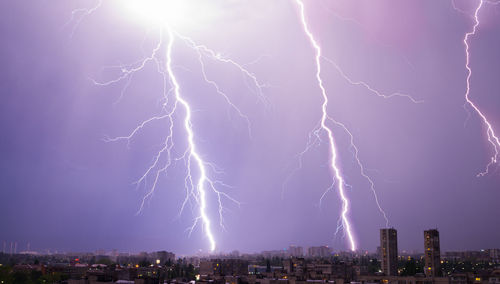 Low angle view of lightning over illuminated buildings in city