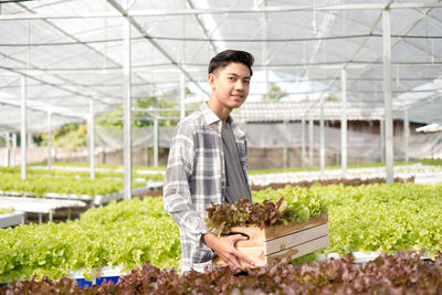 Portrait of a smiling young man standing in greenhouse